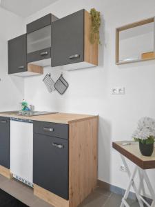 Una cocina con gabinetes negros y de madera y una mesa. en Stockerau Comfort Studio 1BR for 2, en Stockerau