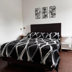 a black and white bed in a bedroom with two pictures on the wall at Santino Apart in Puerto Iguazú +67 photos