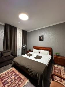 a bedroom with a large bed and a couch at Deluxe SPA-Hotel in Ustʼ-Kamenogorsk