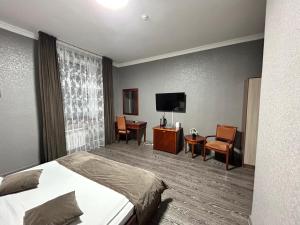 a hotel room with a bed and a flat screen tv at Deluxe SPA-Hotel in Ustʼ-Kamenogorsk