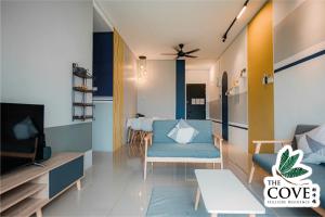 a living room with blue chairs and a tv at Ipoh Tambun Waterpark Apartment The Cove Hillside in Ipoh