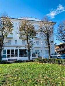 a large white building with trees in front of it at Residence Cigno in Rimini