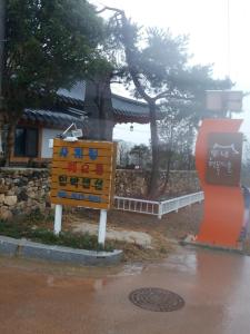 a sign in the rain next to a building at Suncheon Sagyejeol Haeoreum Hanok Pension in Suncheon +5 photos