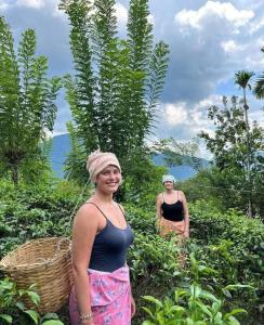twee vrouwen staand in een plantenveld bij Sinharaja Hostel 114 in Deniyaya