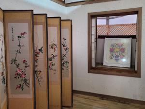 a room with paintings of flowers on the walls at Paju Hanokaeseo Harureul in Paju