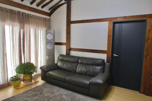 a black leather couch in a living room with a door at Naju DorandoranHouse Hanok in Naju