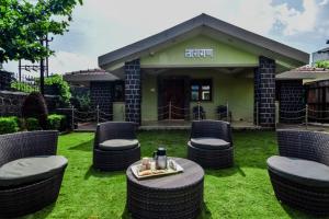 a group of wicker chairs and a table in front of a building at Lifeline Villas - Exclusive 2bhk Taraangan Farm With Huge Private Pool And Lawn Area in Lonavala