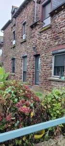 a brick building with windows and flowers in front of it at ST MALON SUR MEL in Saint-Malon-sur-Mel