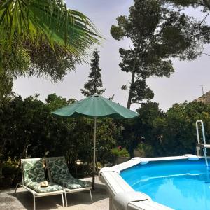 an umbrella and two chairs next to a swimming pool at La Joya del Valle de Ricote in Villanueva de Río Segura