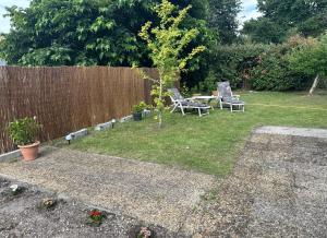 a backyard with two chairs and a table and a fence at Logement agréable sur Le Teich in Le Teich +1 photo