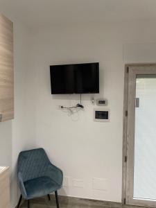 a tv on a white wall with a blue chair at Muschiaturo in Foce Varano
