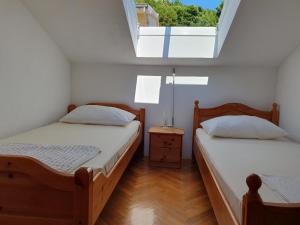 two twin beds in a room with a window at Apartmani Miljak Omiš in Omiš