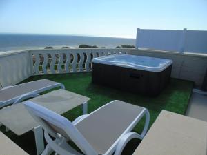 a hot tub on a balcony with chairs and the ocean at Terrazze Naos in San Leone