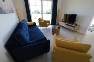 a living room with a blue couch and two chairs at Ferienhaus Landblick in Warstein