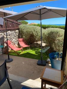 a patio with two chairs and an umbrella at Studio cabine vue mer saint pierre la mer in Fleury