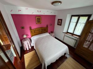 a bedroom with a white bed and a pink wall at Casuca de Susi in Arenas de Iguña