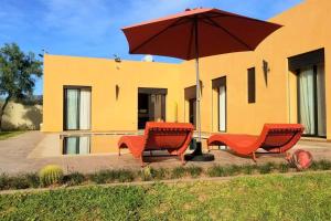 two chairs and an umbrella in front of a house at Villa Familiale in Marrakech