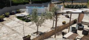 a patio with a pool and chairs and trees at Trullo Monticello in Martina Franca