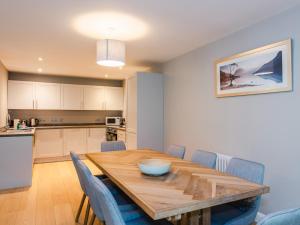 a kitchen and dining room with a wooden table and blue chairs at Mountain Hare Apartment in Kingussie +39 photos