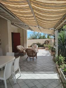 um pátio com uma mesa, cadeiras e toldo em Sunset Villa em Torre Lapillo