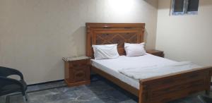 1 cama con cabecero de madera en una habitación en Mashal Palace, en Nathia Gali