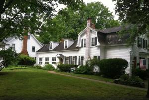 a white house with a black roof and a yard at Admiral Peary Inn in Fryeburg
