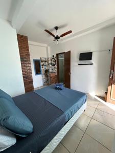 a bedroom with a blue bed with a ceiling fan at Pousada Brisa da Praia in Arraial do Cabo