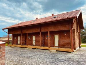 a large wooden cabin with a red roof at Cozy Cabins Vydmantai in Kiauleikiai