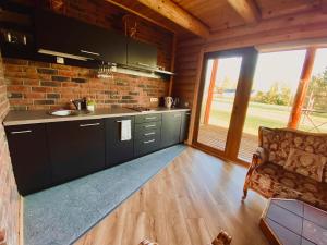 a kitchen with black cabinets and a brick wall at Cozy Cabins Vydmantai in Kiauleikiai