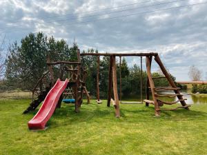 a playground with a red slide at Cozy Cabins Vydmantai in Kiauleikiai