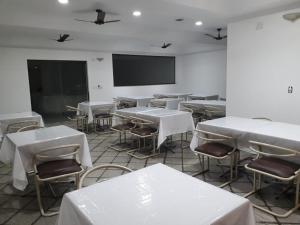 a classroom with white tables and chairs and a screen at Martha Office Hotel in Bauru
