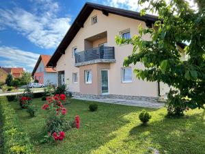a house with a balcony and flowers in a yard at Apartman Naturalis flumen in Otočac