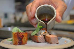 a person is holding a cup of tea with food on a plate at Bella Vista Hôtel, Suites & Maisons in Porticcio