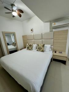 a bedroom with a large white bed with a ceiling fan at Hotel Juan Pablo 2 in Ríohacha