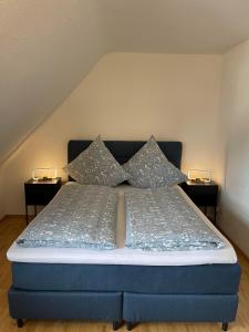 a bed with two pillows on it with two lamps at Ferienwohnung am Kelterplatz in Löwenstein