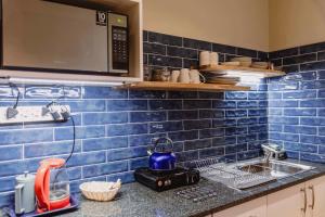 a blue tiled kitchen with a sink and a microwave at Mitford-on-Sea in Morganʼs Bay +121 photos
