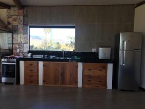 een keuken met een roestvrijstalen koelkast en een raam bij Casa 422 - Loft Oliveira in Santana do Riacho