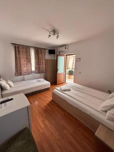 two beds in a room with wooden floors at Pensiunea Silvia in Baile Felix