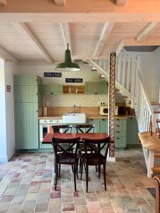 a kitchen with green cabinets and a table and chairs at La Maison du Pêcheur in Verdun-sur-le-Doubs