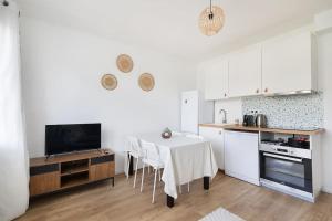 a kitchen with a table with chairs and a television at Appartement Paris CDG Parc Expo Stade in Aulnay-sous-Bois