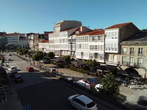 a city with buildings and a street with cars at Pensión La Plaza in Betanzos