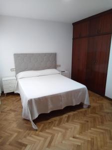 a bedroom with a white bed and a wooden floor at Pensión La Plaza in Betanzos