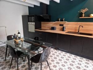 a kitchen with a glass table and chairs and a sink at Maison 2 à 4 pers Spa Sauna in Saint-Victurnien