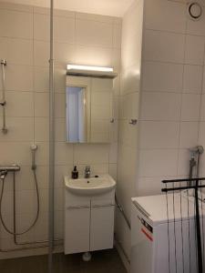 a white bathroom with a sink and a shower at Viihtyisä huoneisto lähellä palveluita in Pieksamaki