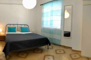 a bedroom with a bed with blue pillows and a window at Fysis Panorama spectacular view in Porto Rafti