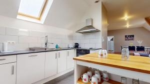 une cuisine avec des armoires blanches et un comptoir en bois dans l'établissement Le nid perché Mulhouse, à Mulhouse