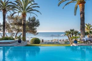 a swimming pool with palm trees and the ocean at La Villa Mauresque in Saint-Raphaël