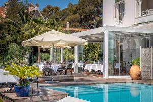 a house with a swimming pool with tables and umbrellas at La Villa Mauresque in Saint-Raphaël