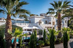 a large white mansion with palm trees in front of it at La Villa Mauresque in Saint-Raphaël