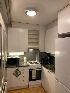 a kitchen with white cabinets and a stove top oven at Saunallinen yksiö keskustassa in Pieksamaki